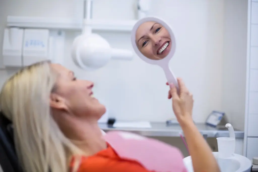 Mujer en consulta mirandose al espejo mientras sonríe