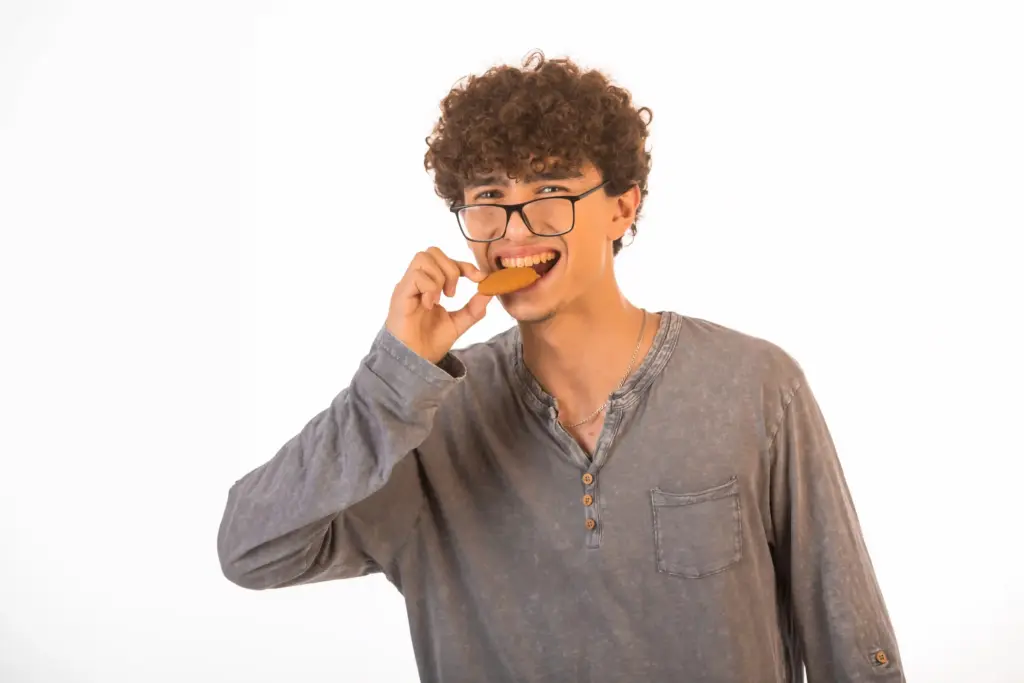 Chico comiendo una galleta por el lado izquierdo de su boca