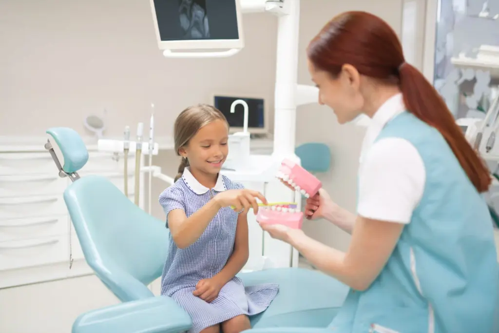 Niña con su dentista cepillando una maqueta