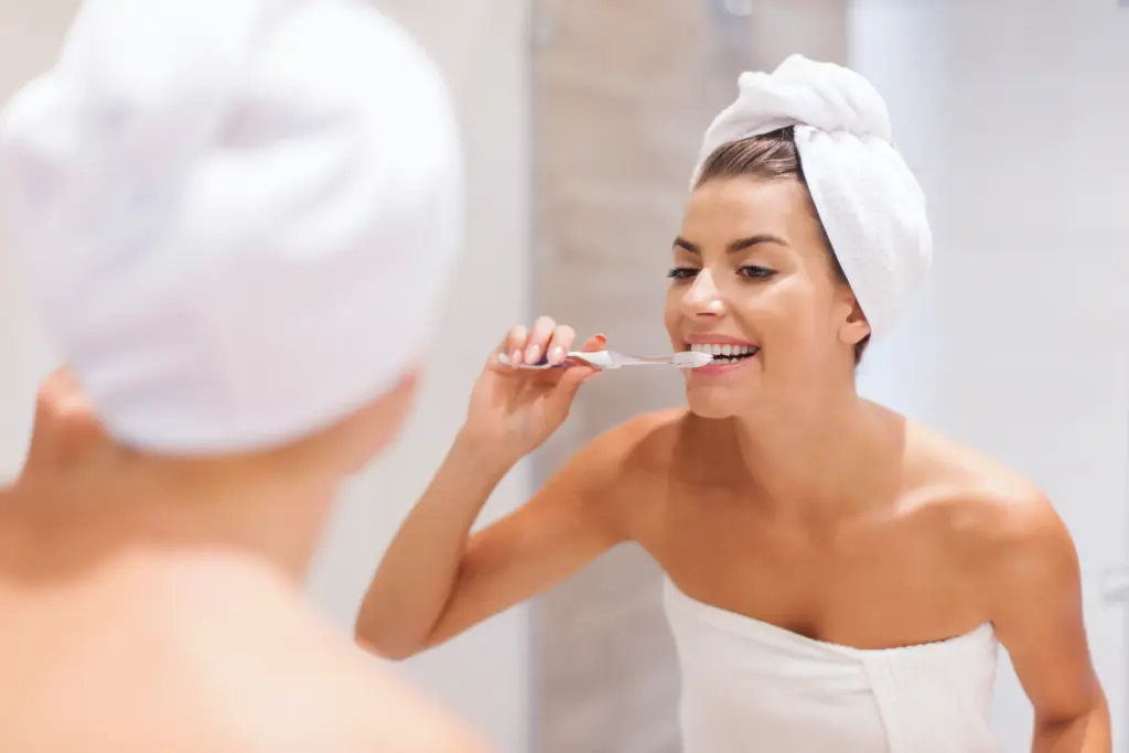 Mujer cepillandose los dientes frente al espejo